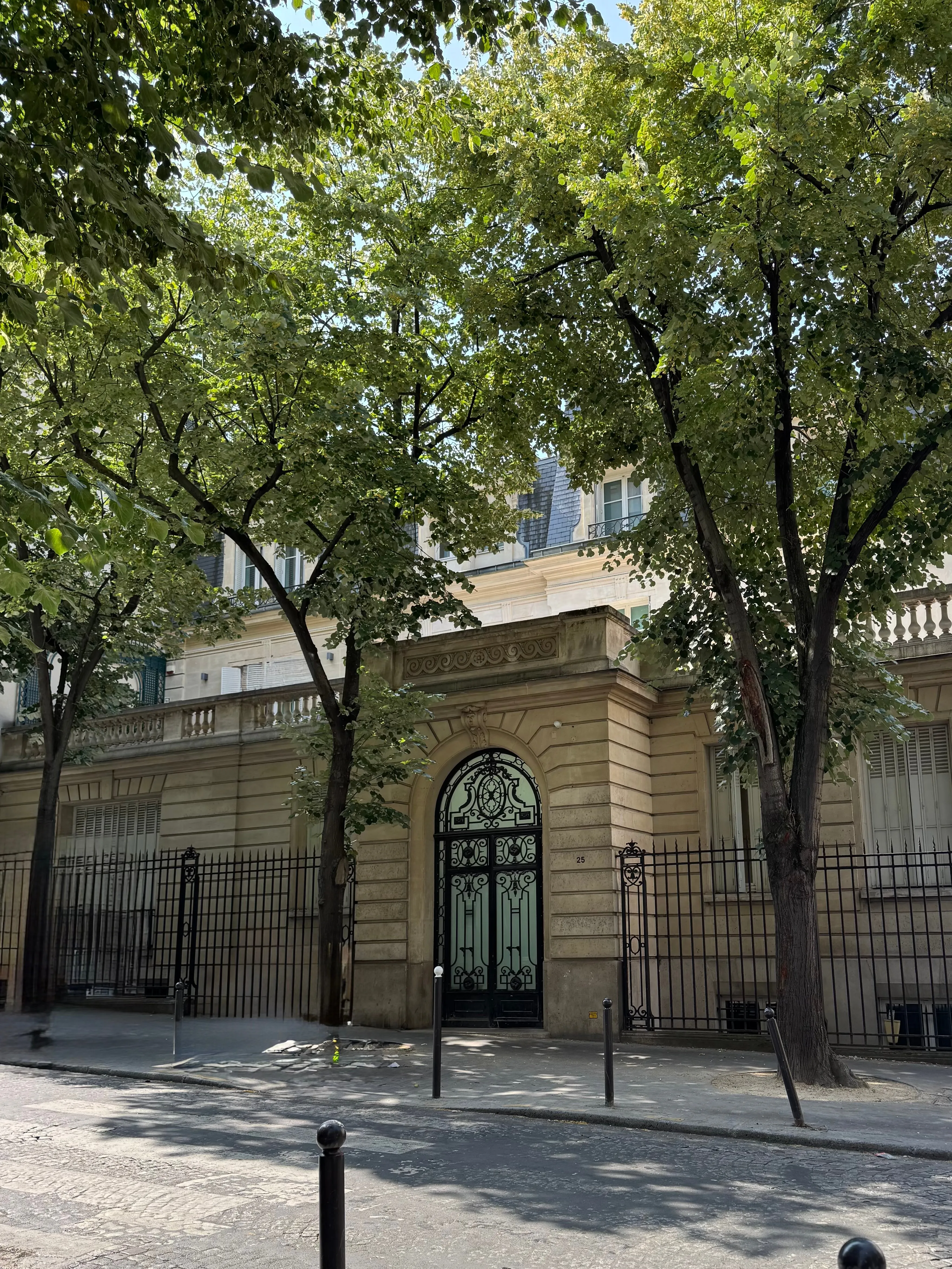 Entrée de l'hôtel particulier, grille et porche sous les arbres