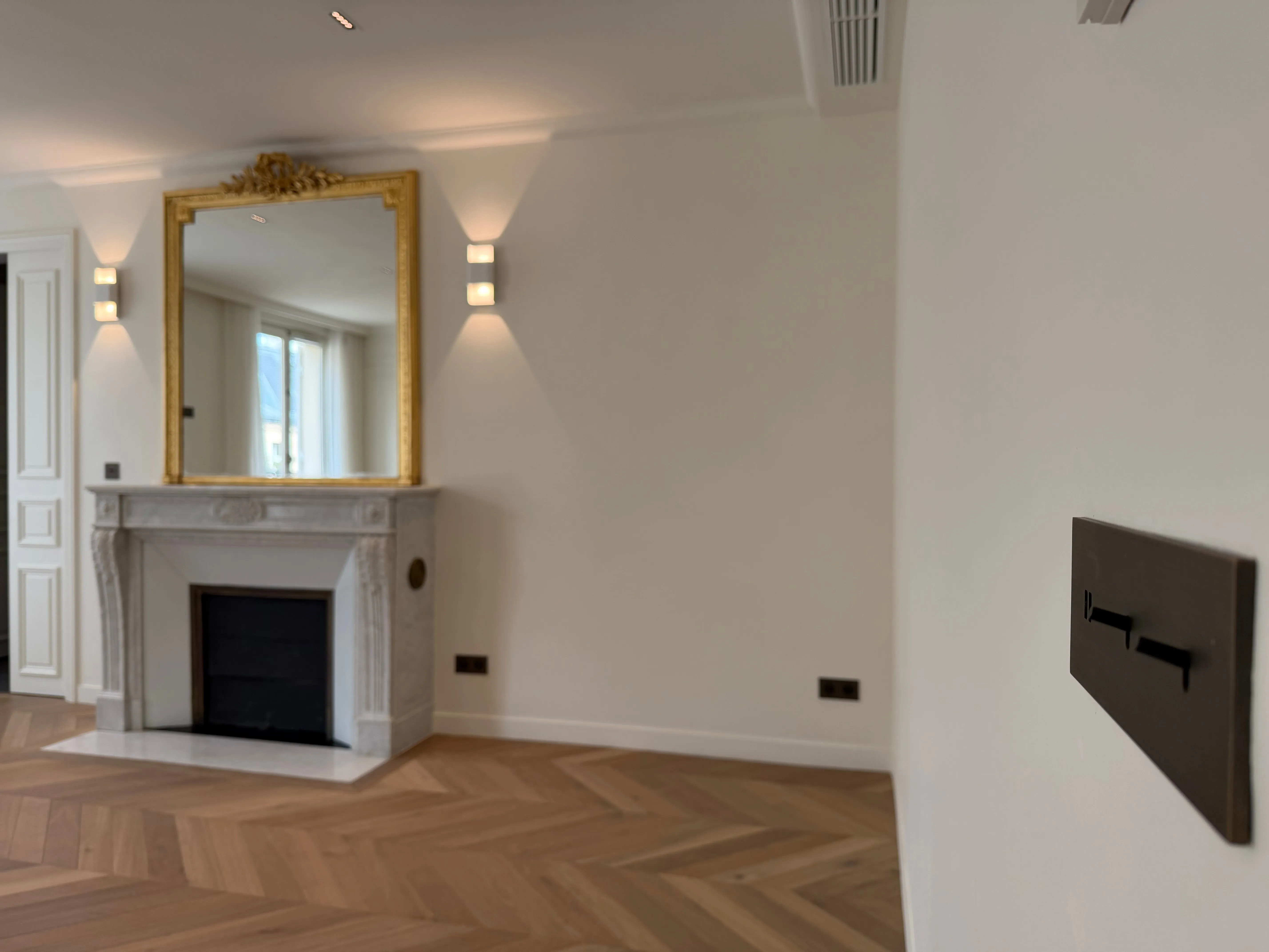 Salon avec cheminée en marbre, miroir doré et écran tactile Akuvox