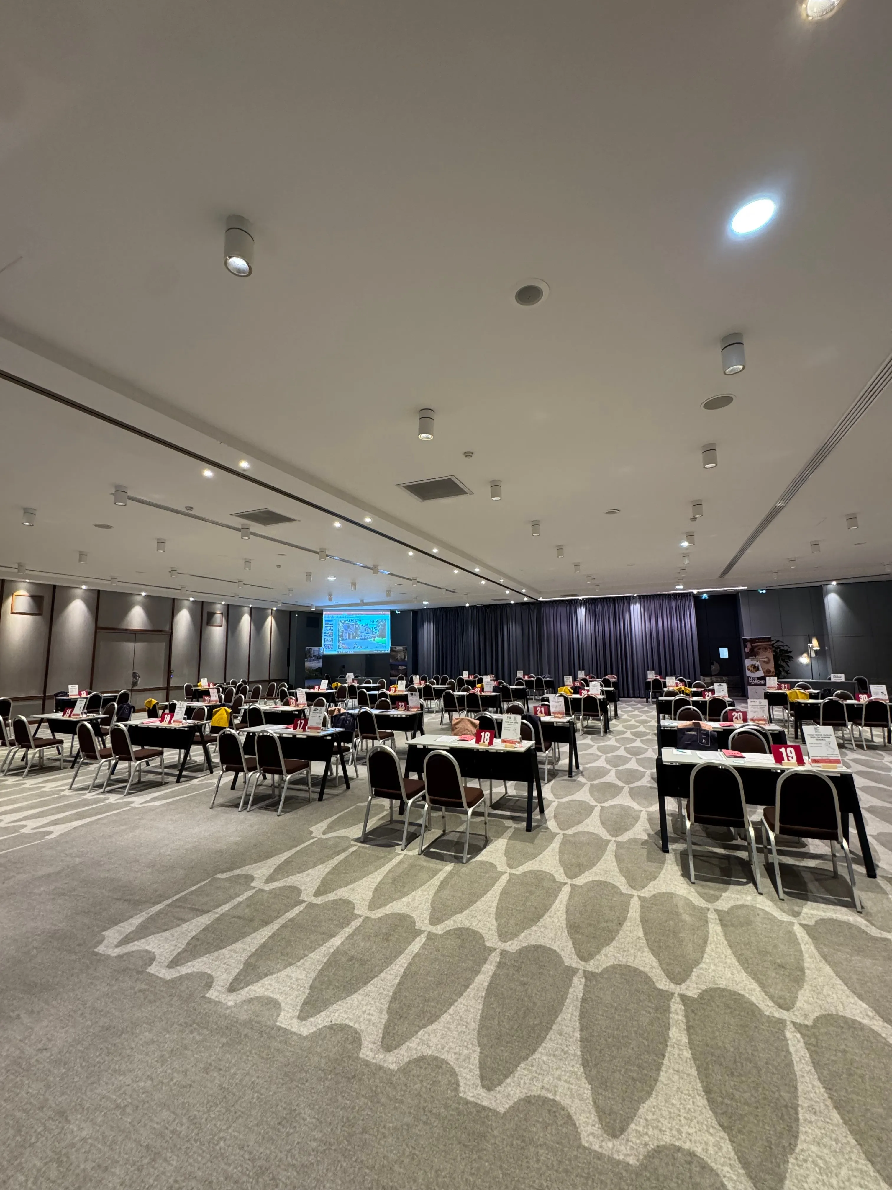 Salle de conférence en configuration banquet, écran et éclairage d'ambiance